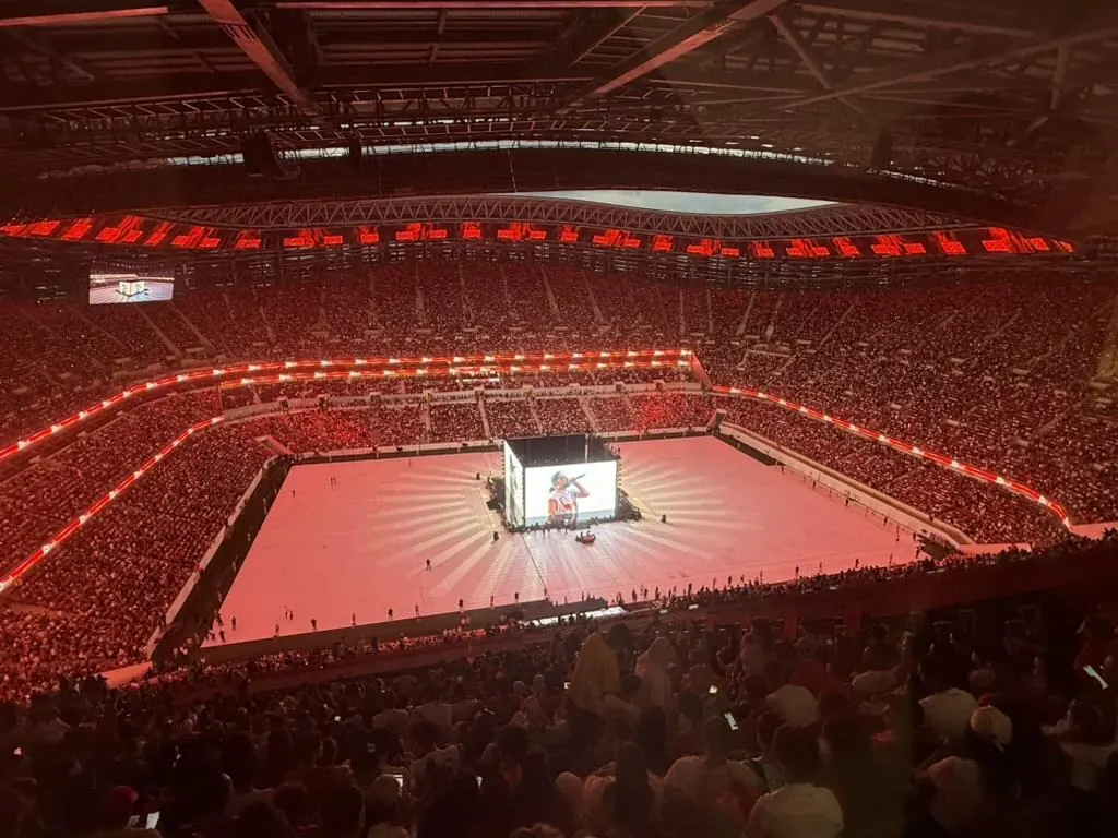 Stade plein, ambiance rouge, scène centrale